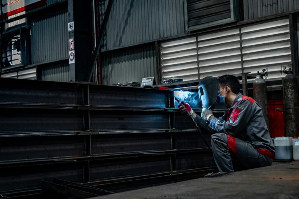 Skilled welder working diligently on metal structures inside a warehouse.